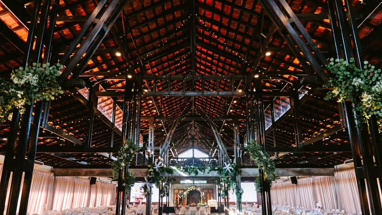 Indoor hall with high timber beams, warm lighting and reception seating